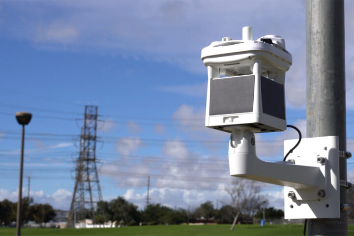 weather station on pole mount in front of blue sky and power line