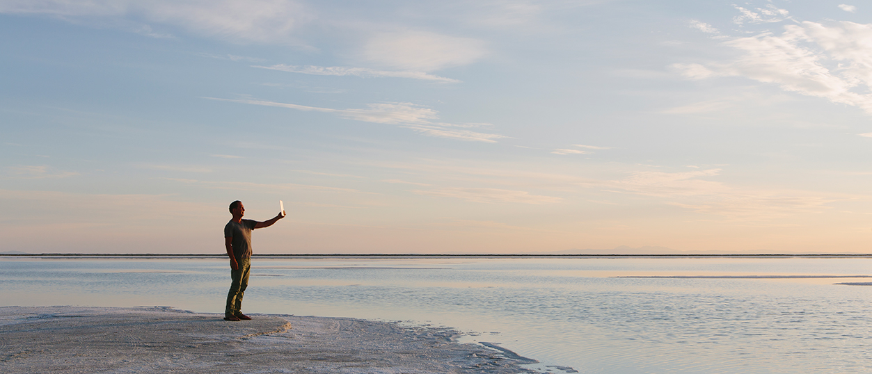 man stands at edge of water at bonneville salt falts in utah