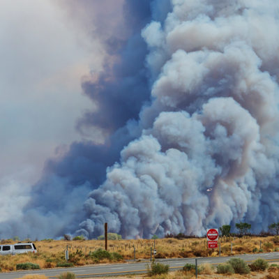smoke from a wildfire rises from a brush field