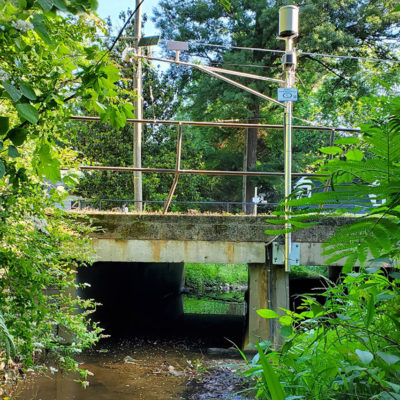 flood sensor and tipping bucket mounted over bridge standing over a creek