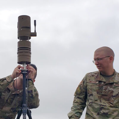 two soldiers set up weather station under cloudy sky